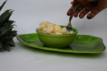 Pineapple or Ananas comosus slices on white background. It is a tropical plant with an edible fruit. It is plant in the family Bromeliaceae. Pineapple pieces in a bowl ready to eat.