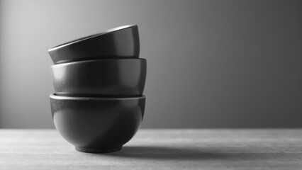 Elegant black bowls stacked on wooden surface create minimalist aesthetic, perfect for modern dining or kitchen decor