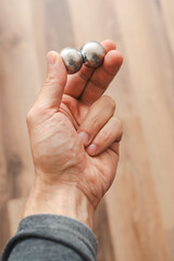 CNC spheres in a man's hand, daylight highlights their form. A symbol of two poles and the force that holds them. A vision of power, balance, and precision.