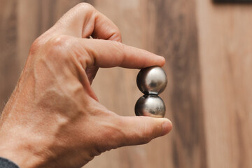 CNC spheres in a man's hand, daylight highlights their form. A symbol of two poles and the force that holds them. A vision of power, balance, and precision.