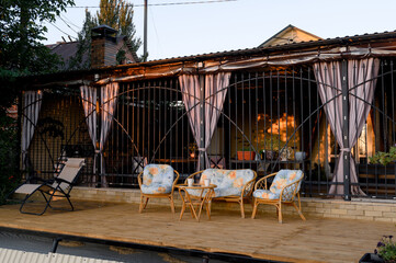 A seating area with rattan chairs and a table on the house's open wooden deck.