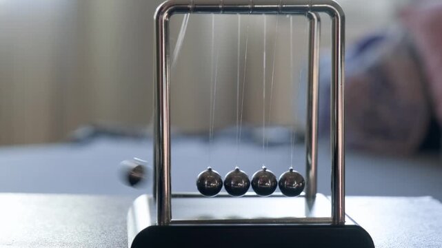 Hand Running Newton's Pendulum Close-Up