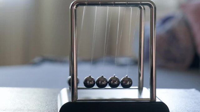 Hand Running Newton's Pendulum Close-Up