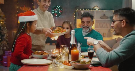 Granddaughter helping grandmother serve Christmas dinner. Heartwarming family holiday moment of love, joy, and multigenerational togetherness at home. - Powered by Adobe