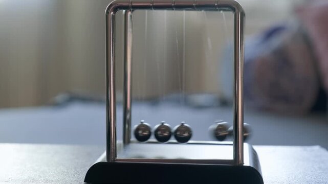 Hand Running Newton's Pendulum Close-Up