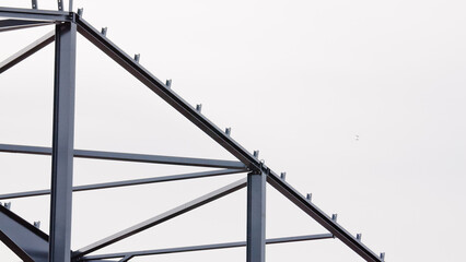 Metal construction, in the photo the structure of the building frame made of metal beams against the background of a gray sky