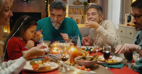 Multigenerational family enjoying Christmas dinner together. Smiling relatives sharing food, talking, and celebrating festive holiday with joy and love at home.