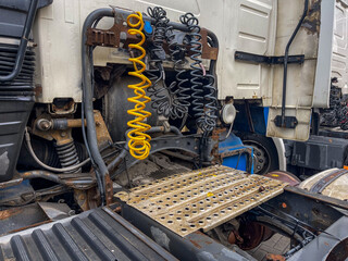 Close-up view of the fifth wheel coupling system and air/electrical connections on a heavy-duty semi-truck tractor, featuring yellow coiled hoses, rust, and mechanical detail, ideal for logistics, tra