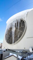 Snowy AC unit with long icicles