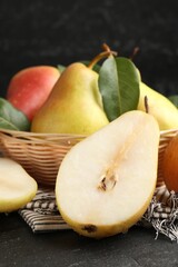 Many fresh pears and leaves in wicker bowl on black table, closeup