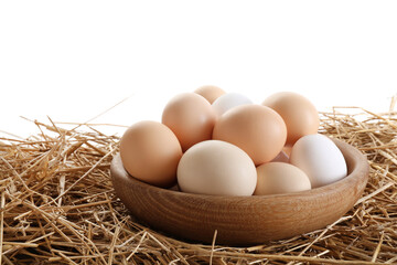 Raw chicken eggs in bowl on straw against white background