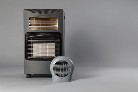 Different types of electric heaters on grey background. Space for text