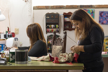 Women hand sewing and machine stitching in workshop
