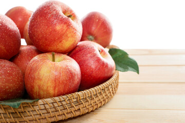 Fresh apples and green leaves on wooden table against white background