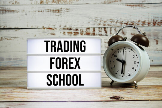 Trading Forex School text with alarm clock on wooden background