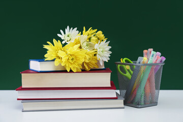 Happy teacher's day. Flowers, books and stationery on white table against chalkboard
