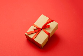 Craft gift box decorated with red ribbon and bow on red background,Christmas present wrap. Xmas delivery
