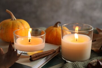 Autumn composition with burning candles and pumpkins on fabric, closeup