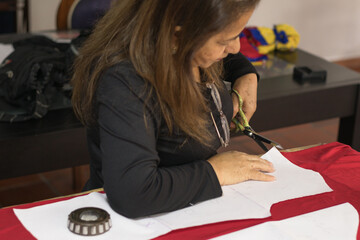 Woman cutting fabric using pattern at sewing workshop