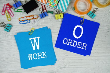 WO - Work Order text on stick note with stationery on concrete background