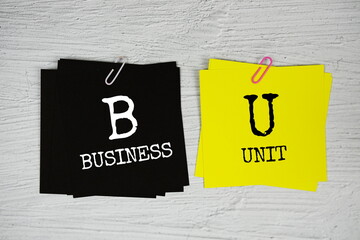 BU - Business Unit text message on stick note on concrete background