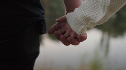 Close-up shot of a couple holding hands, capturing a moment of intimacy and connection during a serene outdoor walk. Couple Holding Hands Gently on a Romantic Walk Outdoors - Powered by Adobe