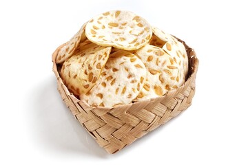 Keripik Tempe or Tempeh Chips in bamboo basket. Isolated on white background with copy space. Traditional Indonesian food are made from soybeans mixed with rice flour then sliced ​​thinly