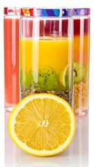 Three colorful smoothies in clear glass containers, topped with colorful lids. A sliced lemon sits in the foreground