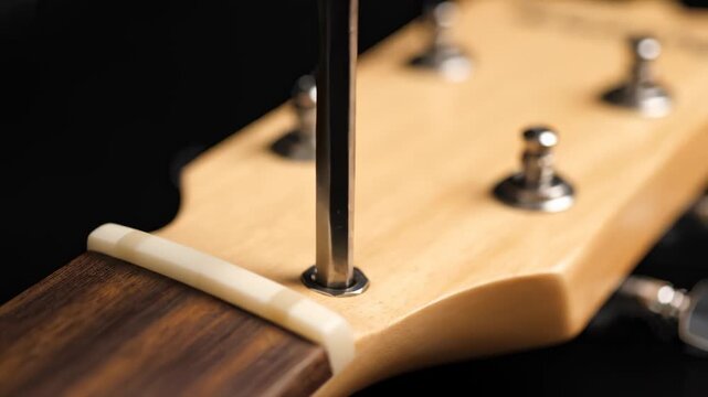 Tightening Tuning Pegs on Electric Guitar With Screwdriver