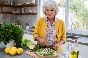 Senior Woman Preparing Grilled Chicken Salad in Kitchen