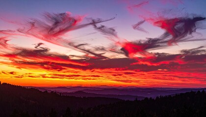Fiery sunset paints the sky with vibrant oranges, reds, and purples over rolling hills