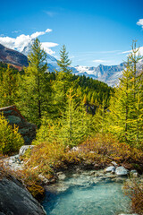 A mountain stream of clear, azure water against the backdrop of a mountain valley in the Alps