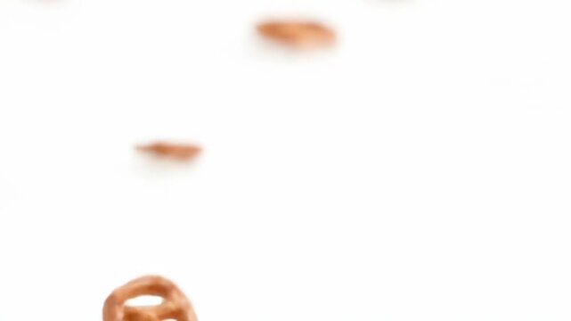 Blurred light brown glazed pretzel snacks scattered across a clean white background