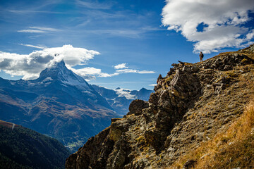 A lone tourist looks down from a high cliff at the summit of the Matterhorn.