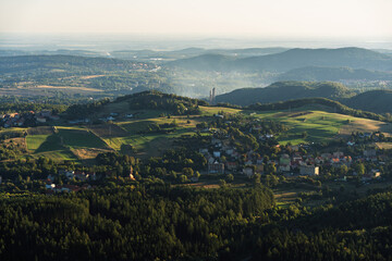 The landscape of Boguszow-Gorce with the city of Walbrzych in the background, seen from the observation tower on Dzikowiec Wielki. The city is surrounded by mountains and forests. 