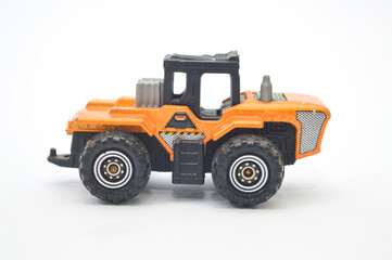 Close-up of a well-worn orange and black die-cast toy tractor, construction vehicle, isolated on a white background. Represents childhood, engineering, industry, play, and transportation concept.