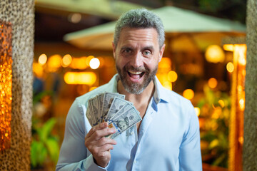 Businessman holding cash. Business man with money. Man counting dollars bills money in cash. Wealthy man with money cash. Business man with cash in urban nightlife. Rich in night city.