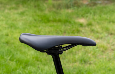 A black bicycle seat is sitting on a grassy field