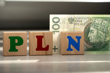 Polish zloty PLN one hundred banknote with wooden blocks showing PLN letters, representing Poland’s national currency, finance, economy and money exchange concept