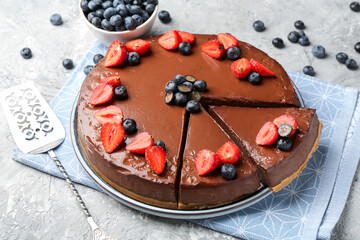 Tasty chocolate cheesecake with berries and server on light grey table, closeup