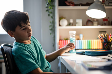Boy studying homework at desk under lamp light