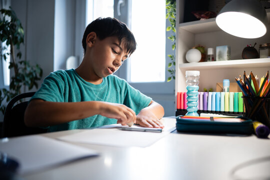 Boy studying erasing drawing for homework at desk