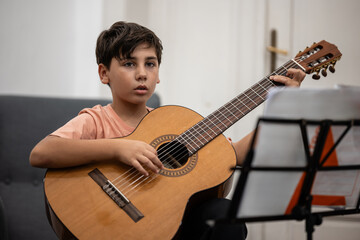 Young boy learning playing acoustic guitar lesson