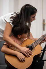 Fototapeta premium Mother teaching son playing acoustic guitar