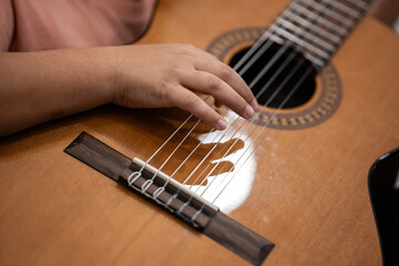 Child hand playing classical guitar strings