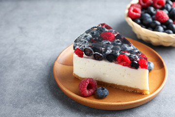 Piece of delicious cheesecake with berries on grey table, closeup. Space for text
