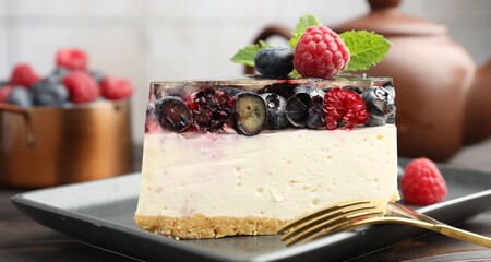 Piece of delicious cheesecake with berries, mint and fork on wooden table, closeup