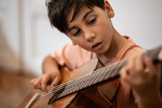 Young boy learning acoustic guitar at home