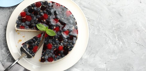 Taking piece of delicious cheesecake with berries at grey textured table, top view. Space for text