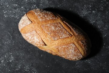 Loaf of fresh bread on grey textured table, top view